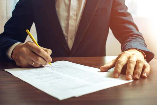 Man businessman signs documents with a pen