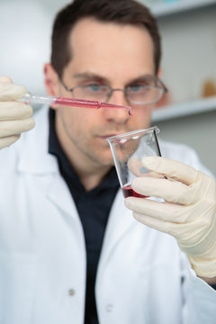 scientist in laboratory holding pipette and test tube