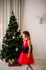 portrait of a girl in a red dress at the Christmas tree - 129197262
