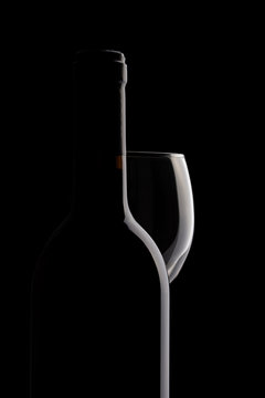 Elegant red wine bottle and wine glass in a black background