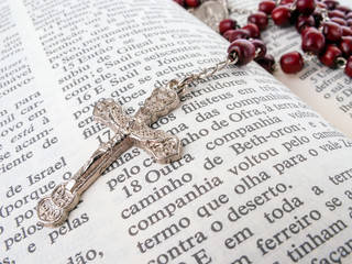 Rosary over an old holy bible written in Portuguese. Close up detail.