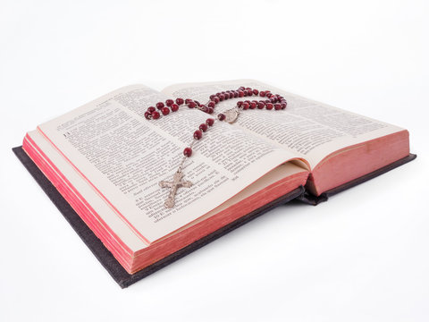 Rosary over an old holy bible written in Portuguese cut out or isolated on white background