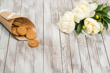 Cookies and pionies flowers on white wooden background. Place for text.