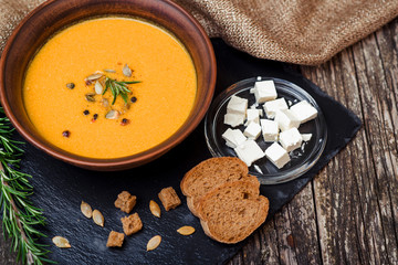 Pumpkin soup with bread crouton on the dark wooden table.