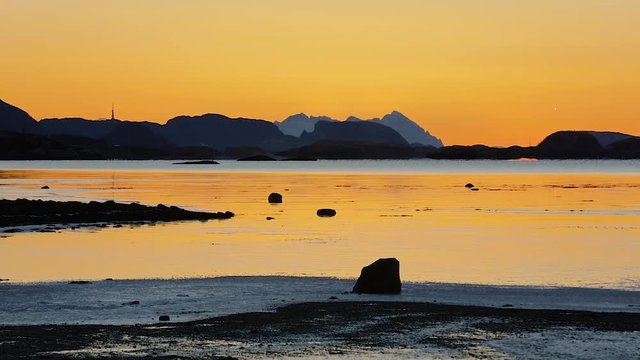 Timelapse of tide and sunset over mountain in a fjord