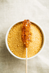 Brown amber sugar crystal on wooden stick.