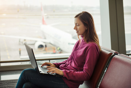 Young woman working on laptop and waiting for flight