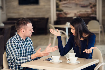 Young couple arguing in a cafe. She's had enough, boyfriend is apologizing. Relationship problems.