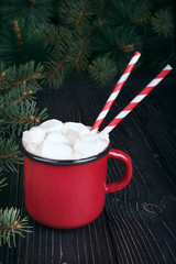 Red enamel cup of hot cocoa with marshmallows on dark wooden bac