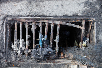 Damaged drain grate with the garbage