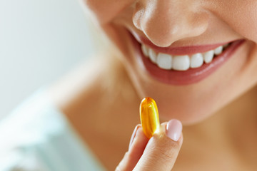 Close Up Of Beautiful Woman Taking Fish Oil Capsule In Mouth