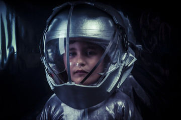 Boy playing to be an astronaut with space helmet and metal suit