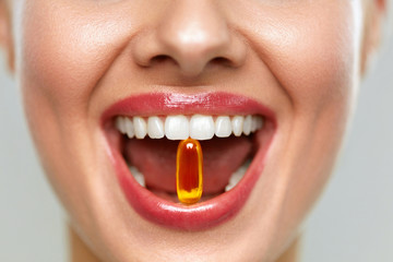 Beautiful Woman Mouth With Pill In Teeth. Girl Taking Vitamins