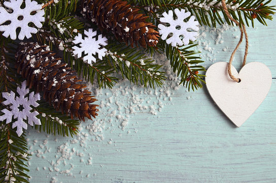 Christmas decoration.Decorative snowflakes,fir cones,heart and snowy fir tree branch on  light blue background with copyspace.Winter holidays,Merry Christmas or Happy New Year concept.Selective focus.