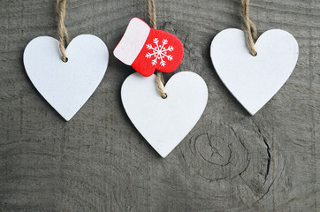 Decorative white wooden Christmas hearts and red mitten on grey rustic wooden background with copy space.Selective focus.Winter holidays,Merry Christmas or Happy New Year concept.
