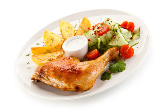 Grilled chicken legs with chips and vegetables isolated on white background