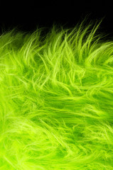 Yellow green fabric on black background vertical. Very soft polyester textile made of synthetic fibers with long hairs. Macro close up material photography, front view.