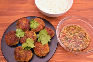 Asian, thai or vietnam style fish and vegetable burgers or fritters with fresh coriander leaves served with boiled rice and homemade fresh sweet chili sauce consist from chili, cucumber, soy sauce.