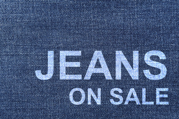 Fototapeta na wymiar jeans on sale word on the denim fabric texture