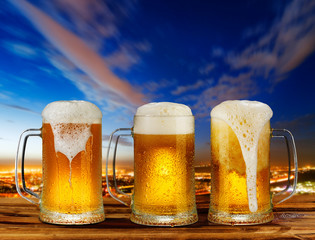 cold glass mug of beer with foam on the background of the street