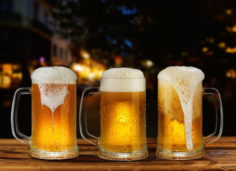 cold glass mug of beer with foam on the background of the street