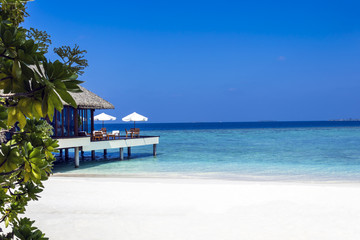 Typically Maldivian Landscape with turquoise ocean, blue sky, white sand beach and beach villas.