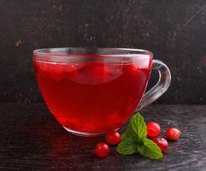 Tea with cranberries in a cup on a black background