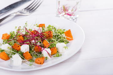 Warm salad with pumpkin, cheese and mini greens.