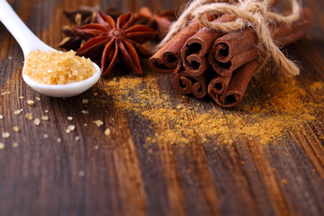 Sticks and powder of cinnamon, anise, sugar cane on the wooden background. selective focus