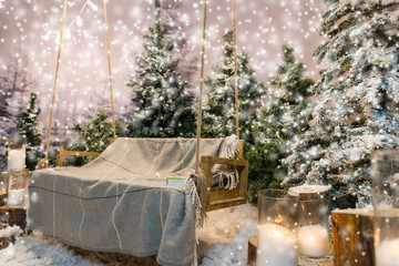 Wooden swing with a blanket and book on it in a snow-covered par