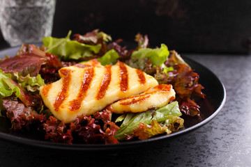 green salad with fried halloumi cheese on a black plate