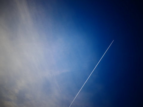 Kondentsstreifen mit Flugzeug am Blauen Himmel