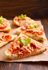 Pizza slices on parchment on wooden background