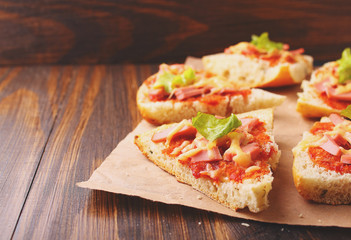 Pizza slices on parchment on wooden background