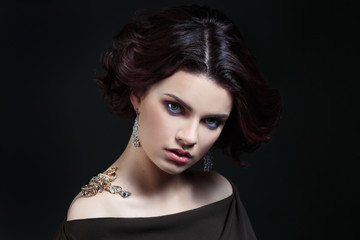 Beauty portrait of a stylish woman in jewelry on your shoulder on a black background.
