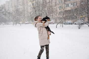 smiling girl with dog in winter snow