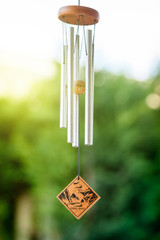 Feng shui chimes with nature in the background with a clear blue sky and defocused tree in the...