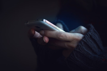 Close up of woman hands in dark sweater hands holding a phone