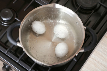 Fototapeta na wymiar White eggs in boiling water into saucepan on the gas stove