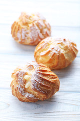 Homemade profiteroles with cream on white wooden table