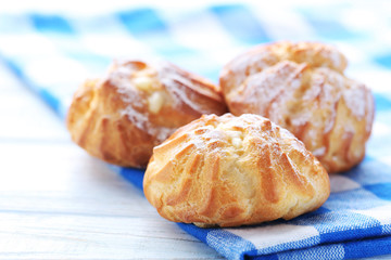 Homemade profiteroles with cream on white wooden table