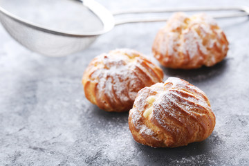 Homemade profiteroles with cream on grey wooden table