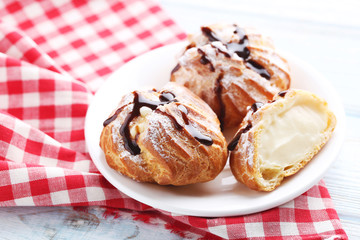 Homemade profiteroles with cream on white wooden table