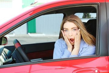 Beautiful young girl sitting in red car