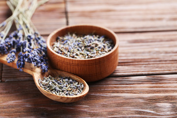 Lavender flowers in bowl and spoon on brown table