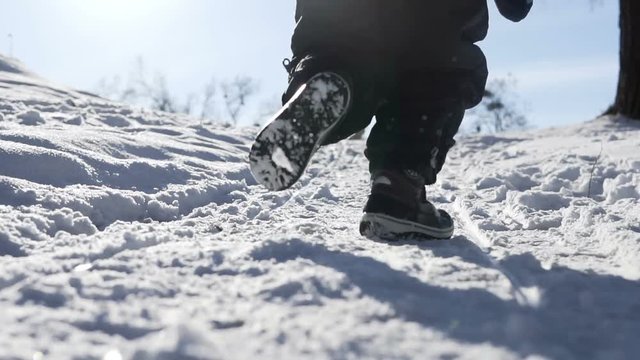 Back slowmotion shot of a kid's snowy park run in winter time