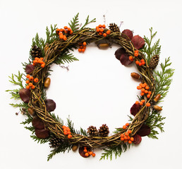 Fototapeta na wymiar Festive wreath of vines with dry leaves, thuja branches, rowanberries and cones. Flat lay, top view