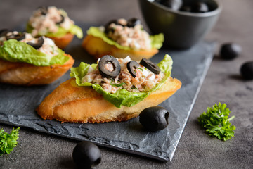 Baguette slices with tuna meat, onion, olives, egg and lettuce