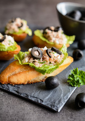 Baguette slices with tuna meat, onion, olives, egg and lettuce