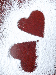 silhouettes of two hearts on a red plate sprinkled with powdered sugar
